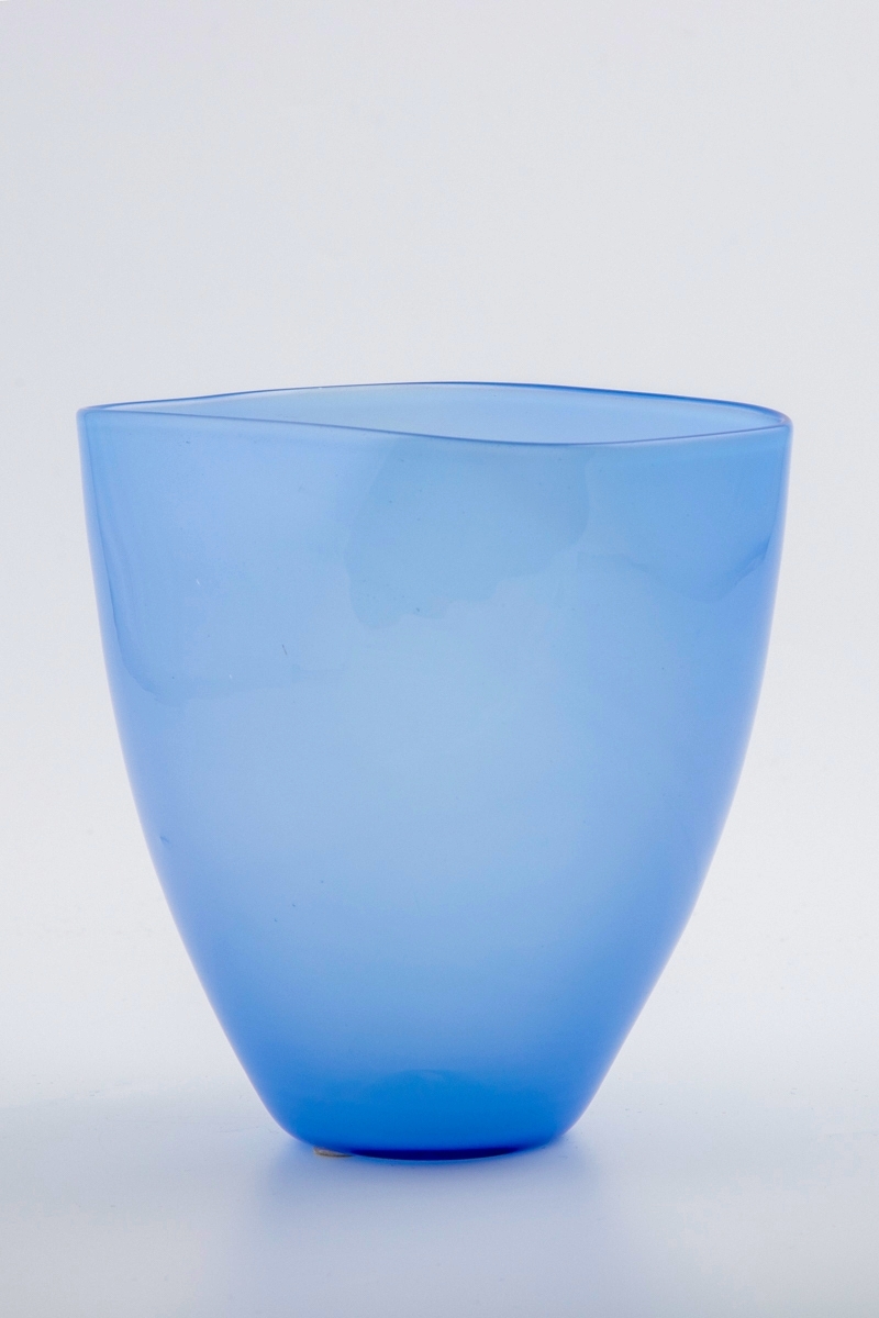 Konisk vase utført i lyseblå opaliserende glassmasse. Korpus hviler på en sirkulær fot, mens munningsranden er rektangulær. Noe hevet bunn med rester av puntemerke.