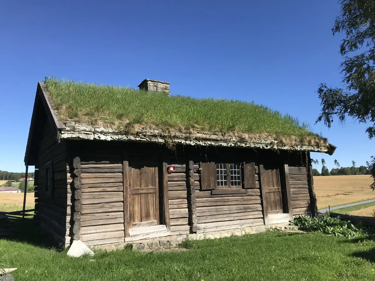 Bildet viser bryggerhuset. Huset er laftet og har torv tak.