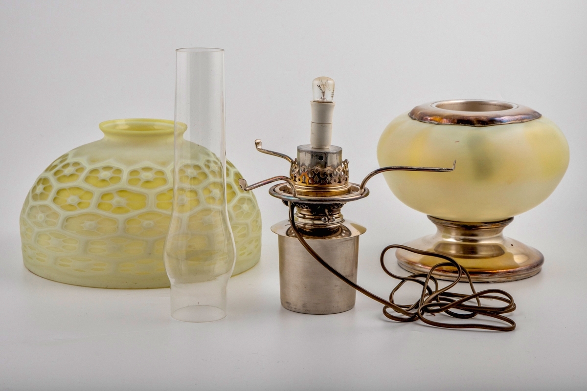 Bordlampe for parafin i farget glass. Lampen hviler på en sirkulær fot i forsølvet bronse. Oljehuset er plassert i lampens nedre del, og er innkapslet i en ovalformet kule av opakt glass med et grønnlig skjær. Brenneren og skruen – sistnevnte for å justere veken – er også utført i forsølvet bronse. Det sylindriske lampeglasset, hvis nedre er kuleformet, er delvis skjult under en bred halvkuleformet skjerm. Skjermens ytterside er dekorert med et bikubelignende mønster i lavt relieff, hvor fordypningene har en grønnlig farge, mens de opphøyde partiene er melkehvite.