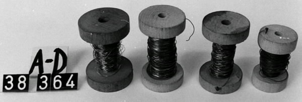 Kaktråd på rulle, av trä och metall. Kaktråden används till armering av ramarna. Träspole med kanter som hindrar metalltråden att lossna. Ett hål löper tvärsigenom spolen, vilket gör det möjligt att fästa spolen i ett rullställ (se invnr 038358). Märkning: b) Silvertråd och John P. c) 185. a) längd 6 cm. Diameter 4 cm. b) Längd 6 cm. Diameter 4 cm. c) Längd 6 cm. Diameter 4 cm. d) Längd: 5 cm. Diameter: 3 cm. 