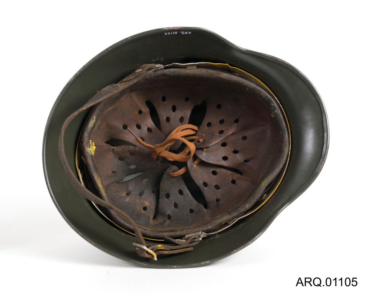 Rund tyskerhjelm med både polstring (indre lærbeskyttelse) og festereimer.
Ventilhull på venstre og høyre side, i tillegg festenagler på hver side og bak som fester innerlær til selve hjelmskallet. Ventilhullet er stanset ut av selve hjelmskallet.
 Innsiden har innbrettet fals og aluminiumsbånd som fester innlær til hjelmskall. Innerlæret har luftehull, en strammesnor i bunnen og det er hakerem festet i stålbåndet.