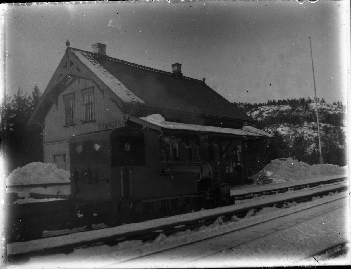 Foto av damplokomotiv type IV nr. 7 SKRIM på Eidanger stasjon 

Fotosamling etter Bendik Ketilson Taraldlien (1863-1951) Fyresdal. Gårdbruker, fotograf og skogbruksmann. Fotosamlingen etter fotograf Taraldlien dokumenterer områdene Fyresdal og omegn. 
Eidanger stasjon, med damplokomotiv.