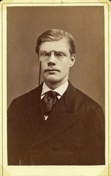 Foto av en ung man med pincené, klädd i mörk yllekavaj med s