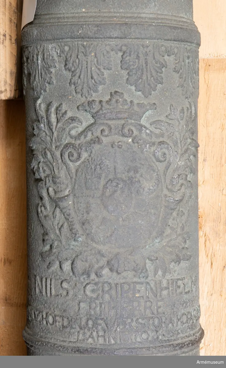 Grupp F I.
Ur kapten F A Spaks katalog 1888: Kanonen är ett enkelt eldrör av metall. Druvan är bladknoppsformig.
BOTTENSTYCKET. Fängpannan är musselformig med uppstående kanter, omedelbart framför kammarsiraterna. På ömse sidor om fäng- pannan finns en S-formigt svängd bladranka (relief). Mellan  kammarbandet och bakfrisen finns Gripenhielms vapensköld (enligt  Spak; relief) samt under densamma inskriptionen (plattrelief):  NILS: GRIPRENHIELM. FRIHERRE. LANDZHÖFDIN ÖFWER STORA KOPARBER.  LÄHN 1703. (Obs! De båda sista bokstäverna i LANDZHÖFDIN är  nästan utnötta men torde vara IN). Omedelbart bakom bakfrisen  finns en bård (i relief) av utbredd akantusblad (bakfrisen utgör  baslinje). Bården saknas på kanonens undersida, på ca 1/3 av  dess omkrets.
TAPPSTYCKET. Tapparnas fria ända är ornerad i stiliserat blomm- önster.
LÅNGA FÄLTET. Omedelbart framför framfrisen finns en likadan  bladbård som bakom bakfrisen. Denna går dock runt hela kanonen. Trumfen trumpetförstärkt med korn och omedelbart bakom detta en liten rund, skålformig fördjupning.

Mått:
Eldrörets längd är 105,5 cm.
Bottenstycket
Bottenstyckets största diameter 14 cm, Bottenstyckets minsta diameter 13,5 cm, Kammarsiraternas bredd 4 cm, Kammarsiraternas bandsläge 8 cm, Kammarsiraternas bandsbredd 1,5 cm.
Tappstycket
Tappstyckets största diameter 13 cm, Tappstyckets minsta diameter 13 cm, B. frisläge 31,5 cm, B. frisbredd 2 cm, Delfinens läge 37cm, Delfinens längd 10 cm, Delfinens höjd 5 cm, Tappläge I 43 cm, Tapplängd 4 cm, Tappdiameter 4,5 cm.
Långa fältet
Långa fältets största diameter ca 12 cm, Långa fältets minsta diameter ca 9,5 cm, Fr. frisläge 47,5 cm, Fr. frisbredd 2 cm, Halsbandsläge 95 cm, Halsbandsbredd  1,5 cm, Trumfens största diameter 12 cm