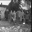 Folksamling med män och kvinnor på baksidan av Brahegatan 75a (Hjertströmska gården). Pastor Robert Svensson tar första spadtaget till Filadelfiakyrkan. Till vänster om pastorn står Harry Forsberg, därefter Abel Svensson, Sven Bardh, Erik Olofsson, Sven Richardsson samt Edvin Andersson.