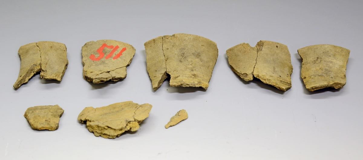 Fra protokollen: 
her foreligger ennå et leirkar (under SM.0511), et lite beger i fragmenter, noe nær Bøe: Jernalderens keramikk, fig. 188. Hverken form eller dekor kan bestemmes nærmere ut ifra de små bitene som foreligger. Feilnummerering, dette kar hører vel neppe til resten av funnet, dog kan det passe inn i tid. Yngre romertid, 4. årh.