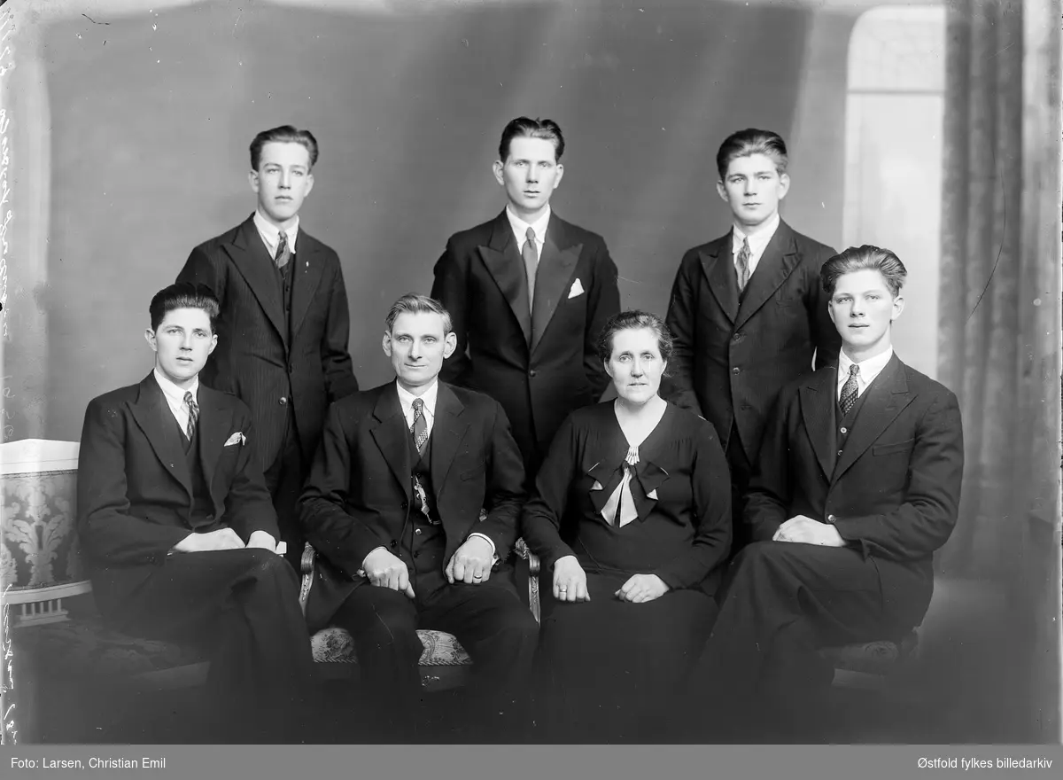 Gruppeportrett av familie i fotoatelier. Bestillers navn: Gustaf Fredriksen.