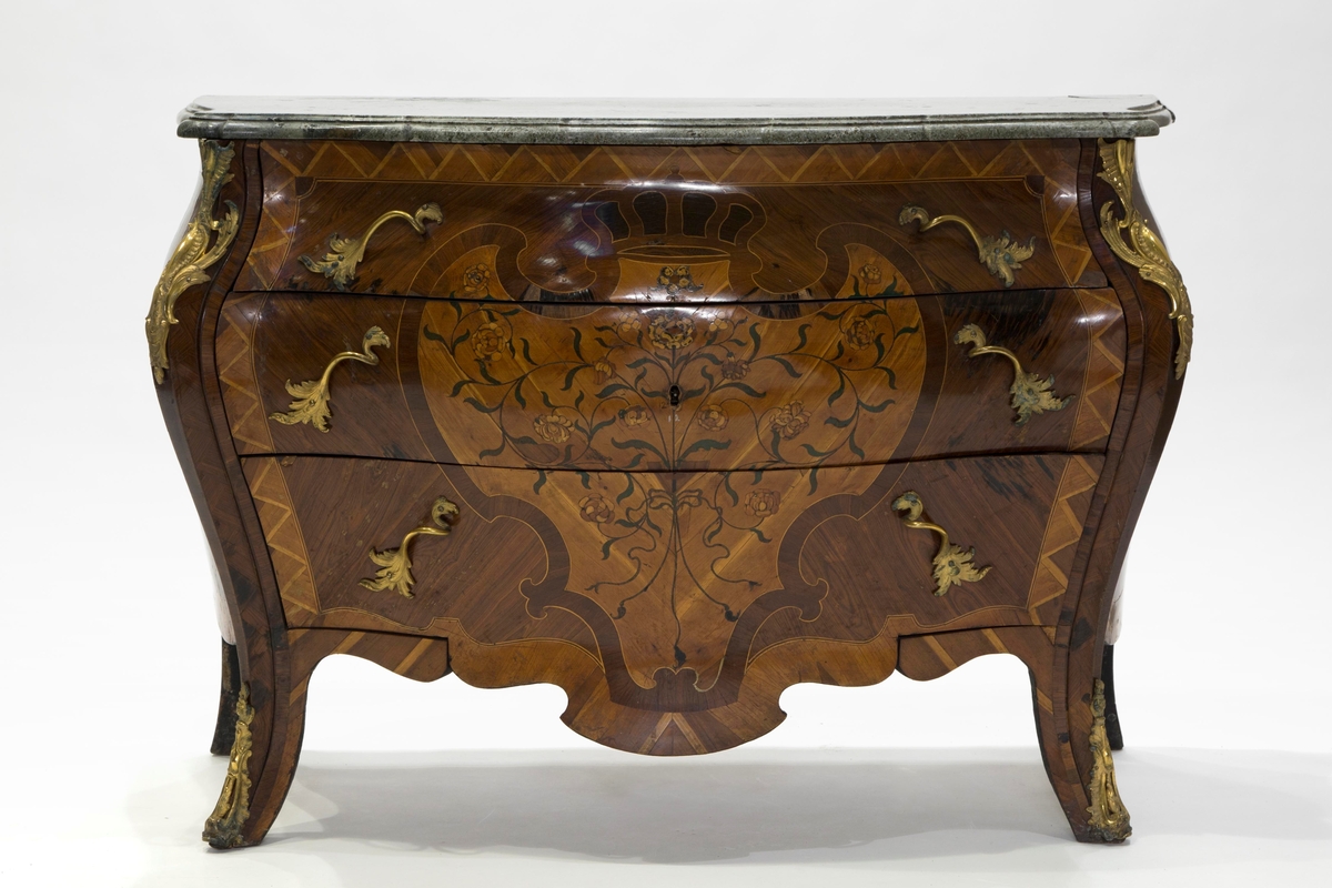 Intarsia  formet som et skjold med krone, og sammenflettede blomstergrener på skjoldet.