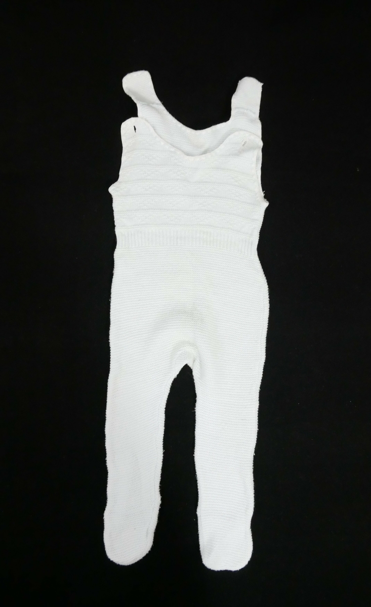 Bukse med fot. Kile i skrittet.Rundklipt i halsen med knepping på kvar side. Markering med vrangbord i livet, mønsterstrikk på overdelen
