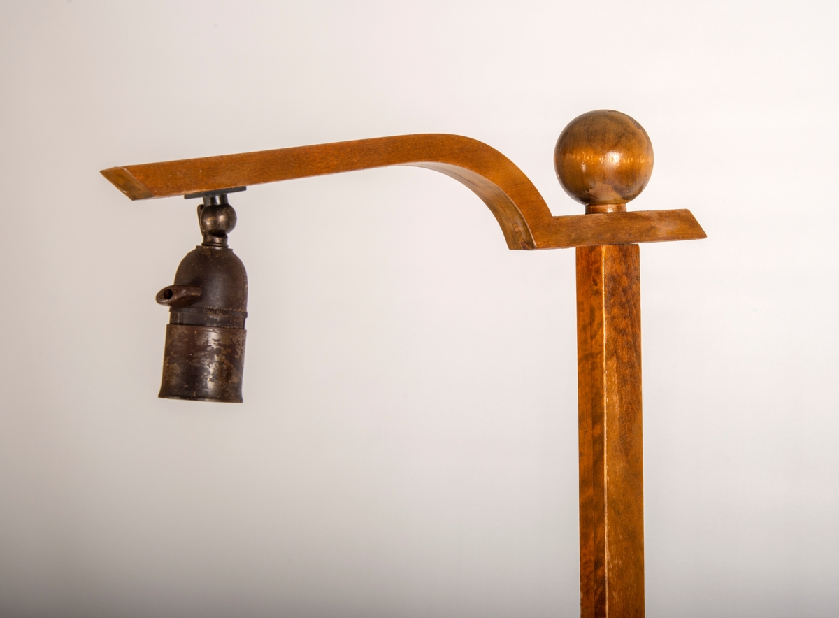 Lampa mangler skjerm. Finerte flater og heltre stativ, beiset og lakkert.  Bordplata kan reguleres i høyden. 