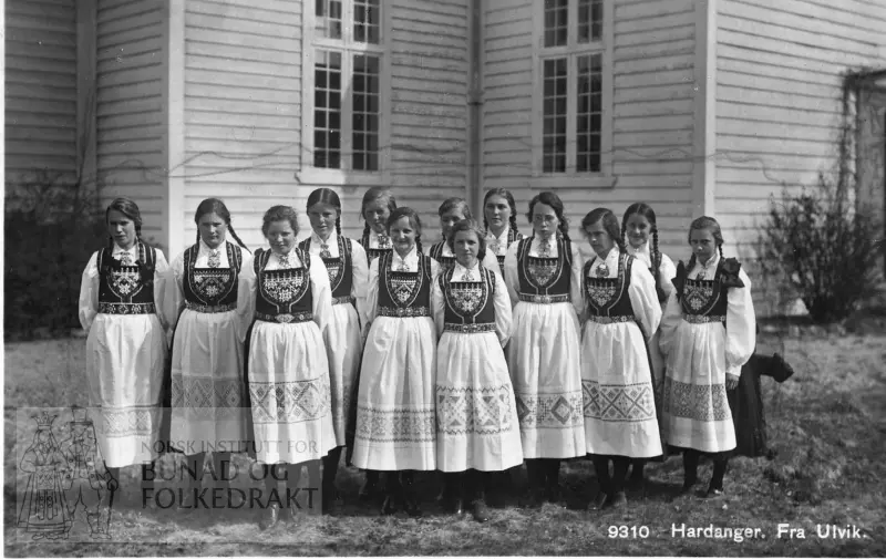 Konfirmantjenter framom Ulvik kyrkje i 1928. Alle er kledde i hardangerbunad. Utan hovudplagg, men håret er fletta.