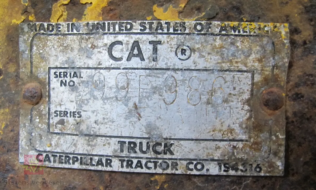 35 tonns gul dumper med 6 hjul, 2 akslinger. Tvillinghjul på bakaksel. 6-sylindret 14,6 liters Caterpillar dieselmotor som yter 400 hk. Dumperkassen har et volum på 17,8 m³. Skiltplater med serienummer 99F986 plassert på rammen og motoren. Metallplater fra produsenten med smørekart og advarsler. Hytte og motordeksler er i glassfiber. Dumperens toppfart er på 69 km/t.