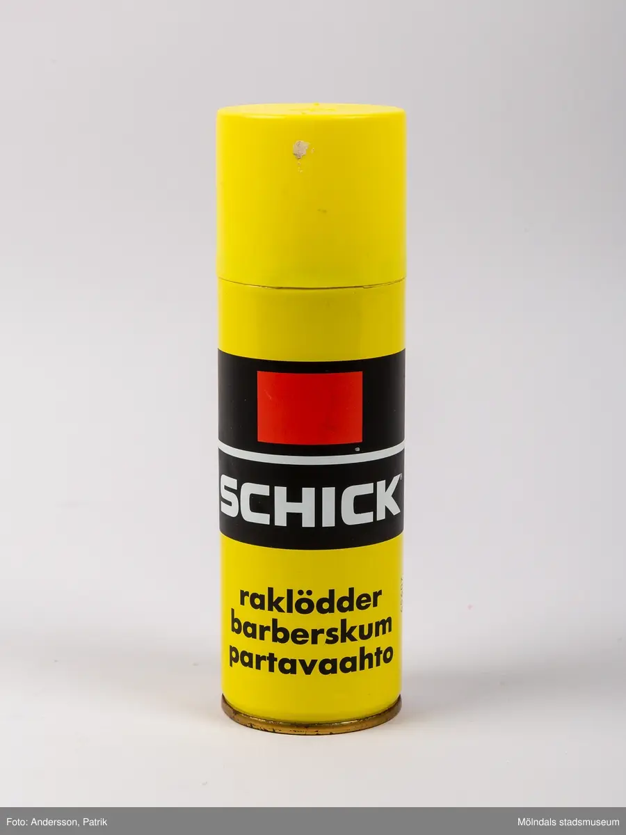 En cylinderformad gul metallburk som innehåller raklödder av märket Schick. Burken har ett gult plastlock. På burkens framsida finns två svarta tjocka ränder. I den övre svarta randen finns en röd rektangel. På den undre svarta randen finns en vit text med varumärkesnamnet Schick påfört.
Längre ned på burken finns en svart text med orden raklödder, barberskum och partvaahto. 

År 1928 fick amerikanen Jacob Schick patent på den första elektriska rakapparaten. Möjligen anknyter raklöddrets produktnamn till denne Jacob Schick. Schick var ett registrerat varumärke.