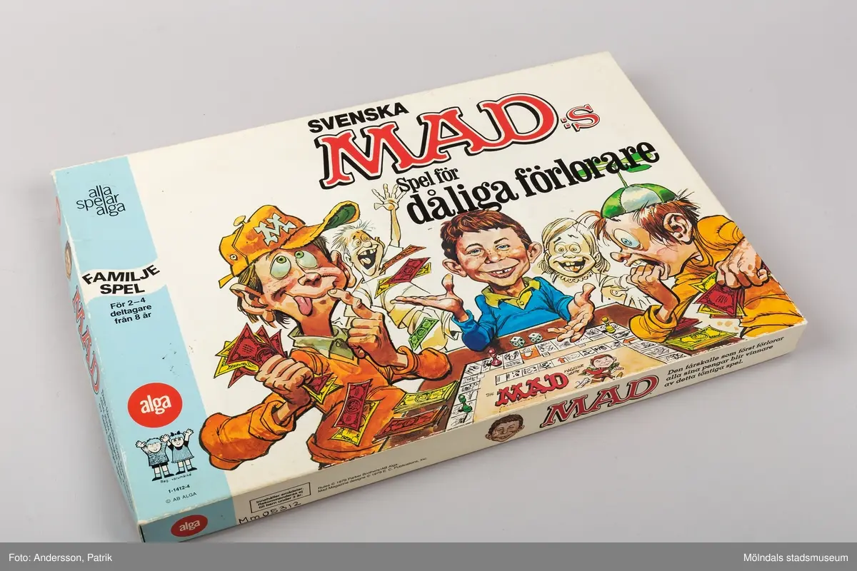 Brädspel i rektangulär pappkartong. På utsidan syns karaktärer från den tecknade serien Mad. Spelet är ett familjespel för 2-4 deltagare från 8 år. Tillverkningsår 1979.