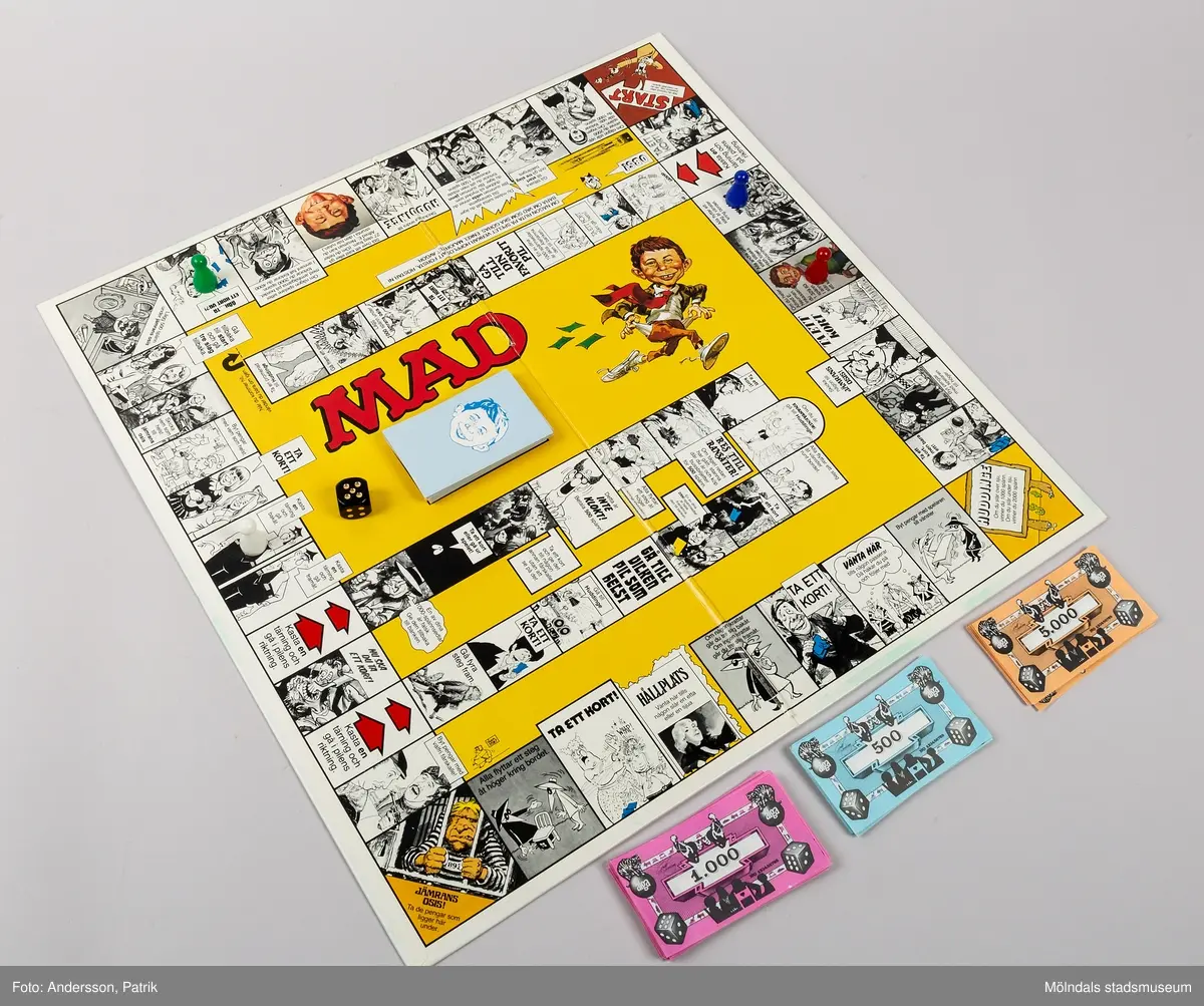 Brädspel i rektangulär pappkartong. På utsidan syns karaktärer från den tecknade serien Mad. Spelet är ett familjespel för 2-4 deltagare från 8 år. Tillverkningsår 1979.