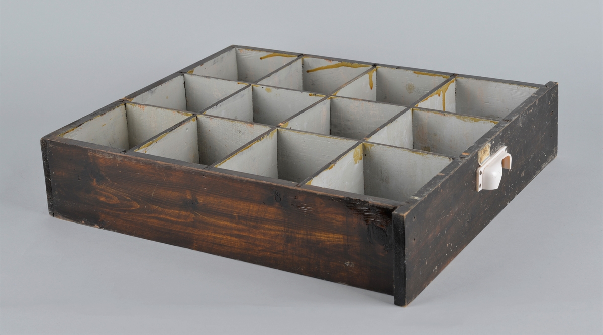 Trekasse for oppbevaring av rasjoneringskort, brukt under og etter andre verdenskrig.
Kassen har en uttrekkbar skuff med flere rom som passer til åpningene i fronten. Håndtaket på skuffen er delvis knust.
Kassen har 12 åpninger i 4 rekker, der det er påmalt tekst: 
1 rekke: X -  X - X 
2 rekke: X - X - kakao
3 rekke: lær - sko - kaffe
4 rekke: mel - fett - sukker