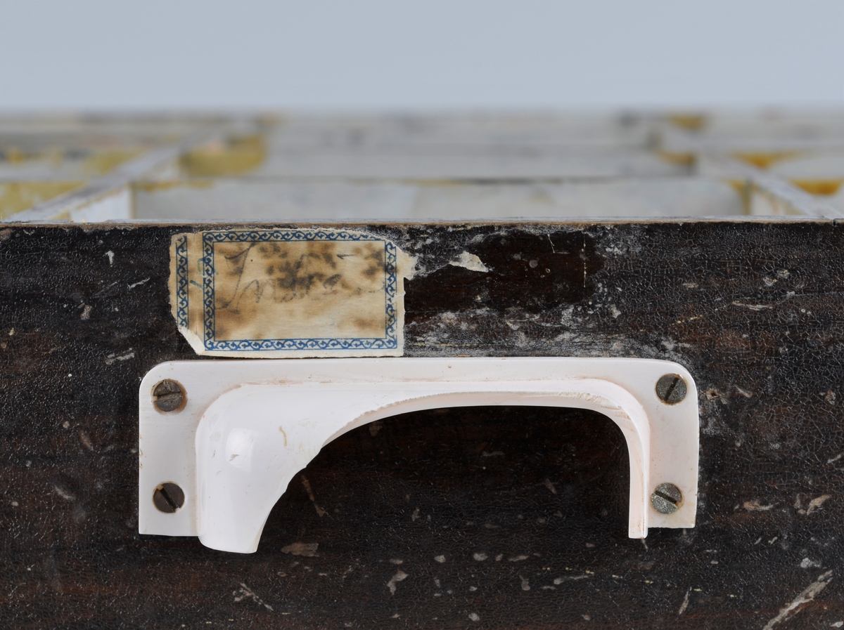 Trekasse for oppbevaring av rasjoneringskort, brukt under og etter andre verdenskrig.
Kassen har en uttrekkbar skuff med flere rom som passer til åpningene i fronten. Håndtaket på skuffen er delvis knust.
Kassen har 12 åpninger i 4 rekker, der det er påmalt tekst: 
1 rekke: X -  X - X 
2 rekke: X - X - kakao
3 rekke: lær - sko - kaffe
4 rekke: mel - fett - sukker