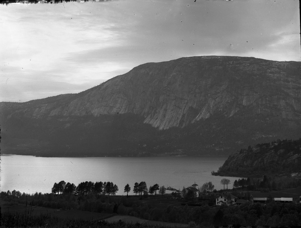 Fotosamling etter Bendik Ketilson Taraldlien (1863-1951) Fyresdal. Gårdbruker, fotograf og skogbruksmann. Fotosamlingen etter fotograf Taraldlien dokumenterer områdene Fyresdal og omegn. 
Motiv med parti av Fyresdal, Moland kirke og prestegård.