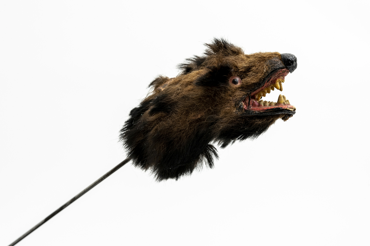 Tekstilhode av hund eller ulv festet på tynn stålpinne. Har tilhørt Sara Fabricius