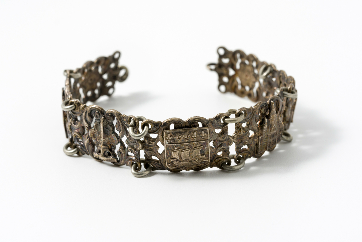 Armbånd i metall dekorert med motiv av blomster og kulturminner/landemerker (f.eks. eiffeltårnet og triumfbuen)