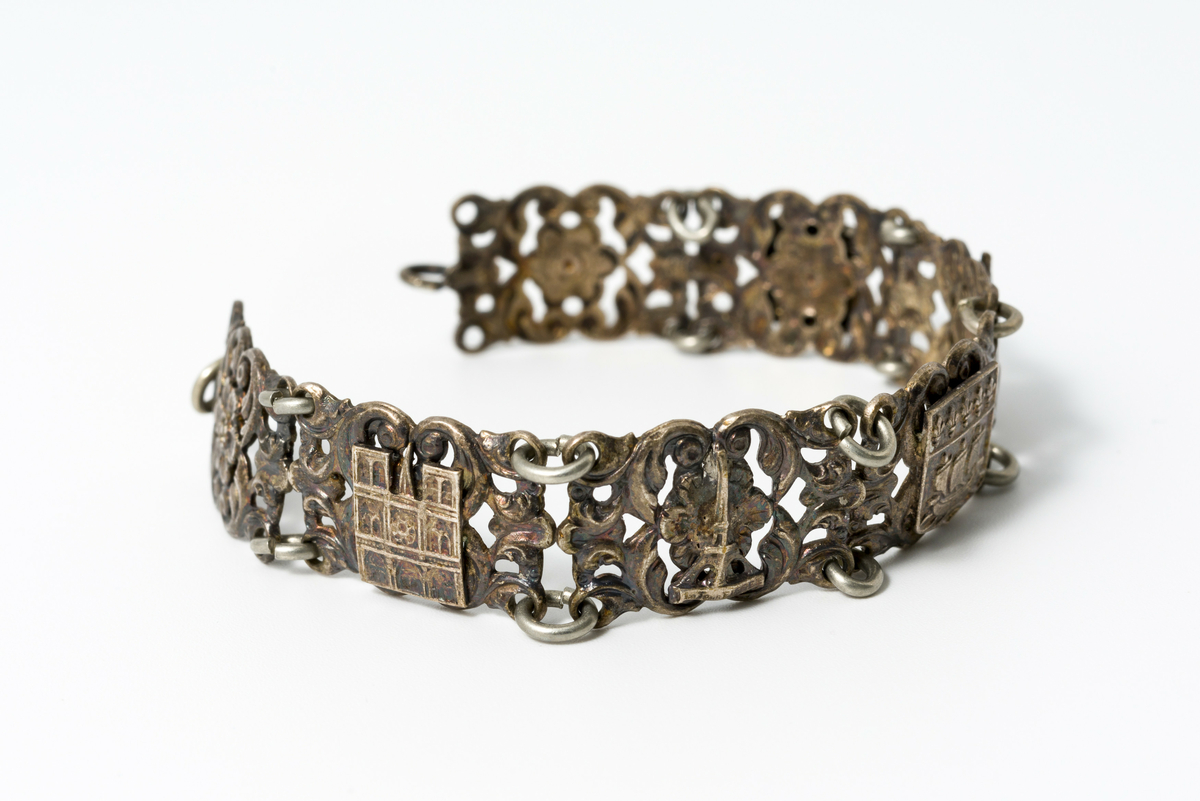 Armbånd i metall dekorert med motiv av blomster og kulturminner/landemerker (f.eks. eiffeltårnet og triumfbuen)