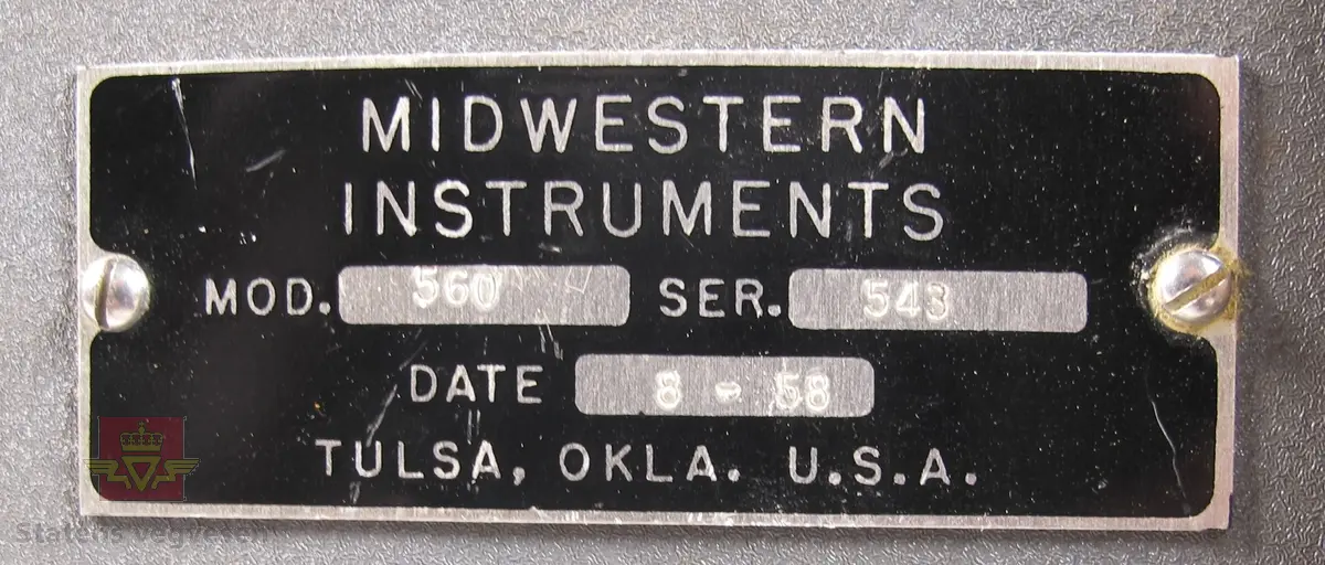 Oscillograf i oppbevaringskasse av treverk, med bærehåntak og låsekasse med nøkkel. Oscillografen er i grålakkert metall med skiltplate som har innskriften MIDWESTERN INSTRUMENTS MOD. 560 SER. 543 DATE 8 - 58 TULSA, OKLA. U. S. A. Den har utgående ledninger som er samlet i en gjennomsiktig gummistrømpe, og i enden sitter det en kobling i plast med 12 tilkoblingspunkter. Klistremerke på toppen med håndskriften Film i kassetten 28/4-64. Oppbevaringskassen er merket med skilt som har innskriften 12 KANALS OSCILLOGRAF KRAFTFORSYNINGENS SIVILFORSVARSNEMD, OSLO. Inni oppbevaringskassen ligger et papirark med håndskrift der det er skrevet ned når det er satt i ny film, og hvor mye film som er benyttet ved bruk, og hvor mange meter som gjenstår.