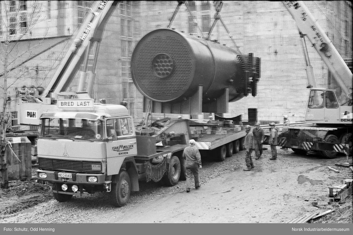 En 70 - tonns dampkjele flyttes fra jernbanevogn til trailer ved hjelp av to kranbiler.