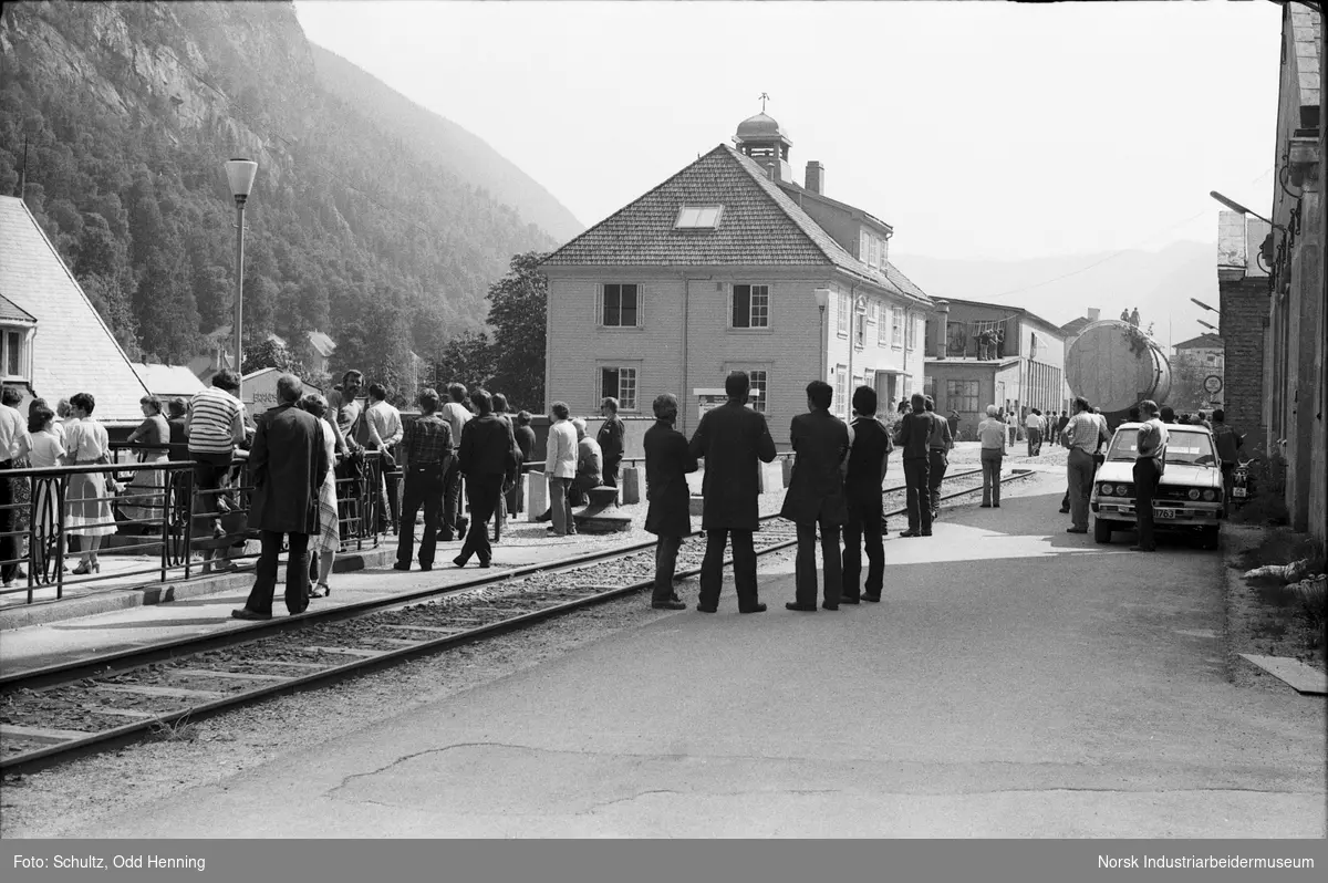 Transport av syretårn til Rjukan Fabrikker. Folk er samlet og ser på tungtransporten ved Kontorbygningen.