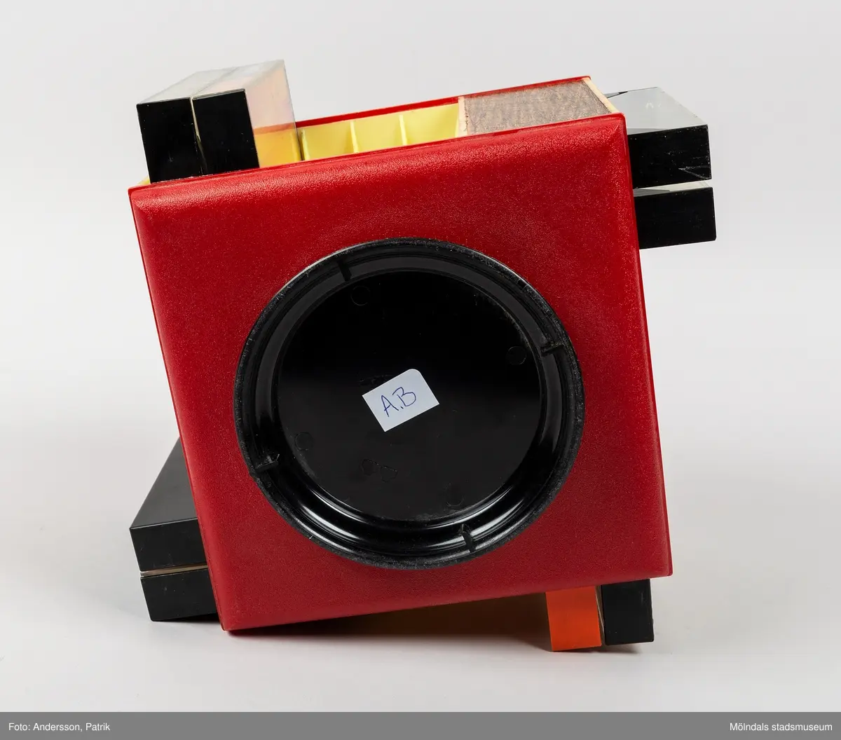 Ett kassettställ av hårdplast för förvaring av kassettband. Stället har en rund fot med manuell snurrfunktion. Kasettställets form är kvadratisk och färgen är röd. Ställets invändiga sidor är ljusgula. Hörnen har en vertikal sida med plast i träimitation. Kassettstället innehåller plats för 20 kassetter. I detta ställ finns 8 kassetter. På ställets ovansida finns en något upphöjd svart cirkel. Inuti cirkelns mitt finns en guldfärgad text med namnet Audio master.
Kassettband introducerades på marknaden 1963 av det nederländska teknikföretaget Philips. De användes för att spela in musik och talinspelningar. Kassettbanden var väldigt populära mellan 1975-1995.