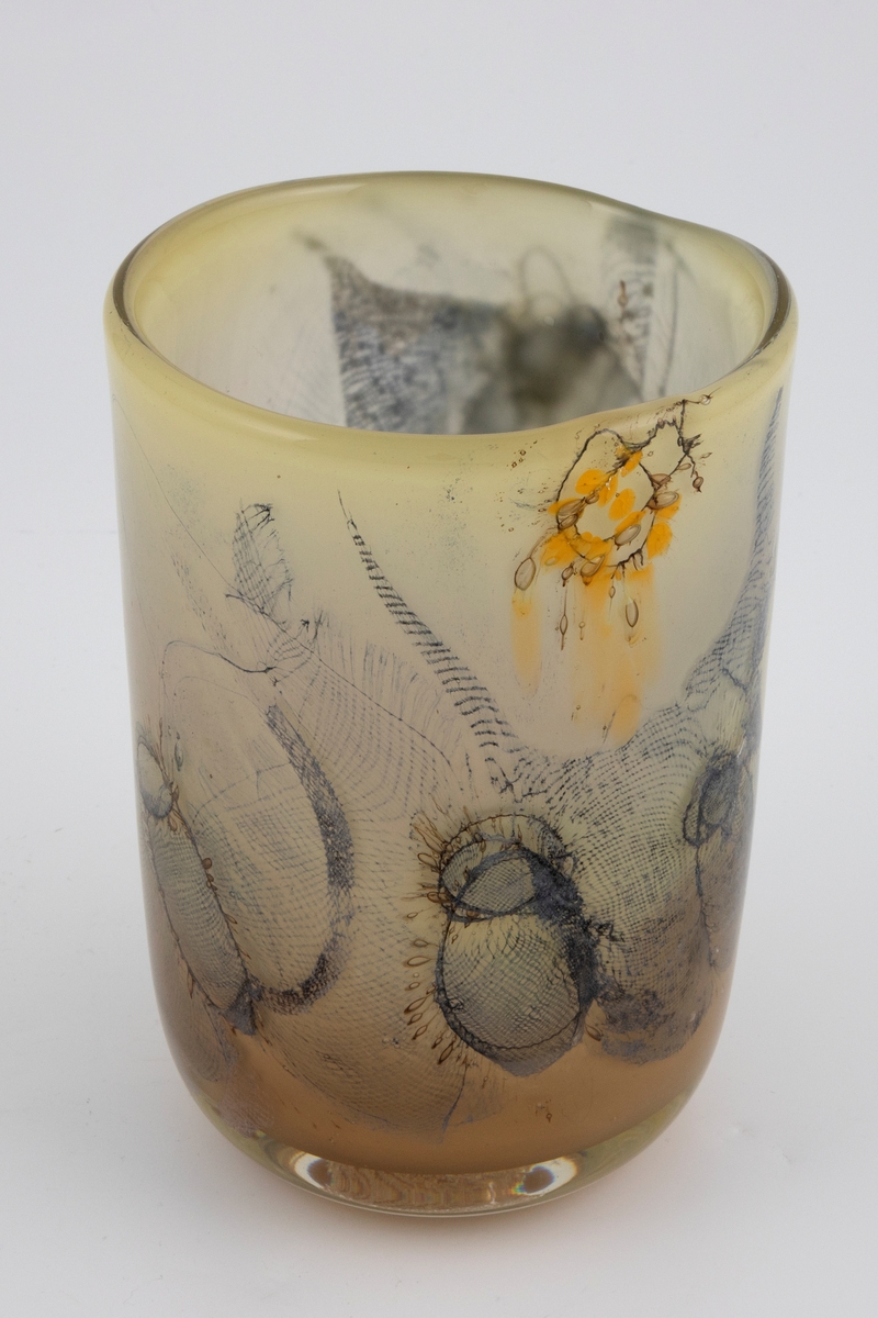 Sylinderformet vase i halvgjennomskinnelig glass. Ujevn munning. Grågrønt underfang som er dekorert med innlagte metalltråder samt partier med finmasket blålig netting. Tidvis brune spetter samt luftbobler i glassmassen. Puntemerke under vasens bunn.