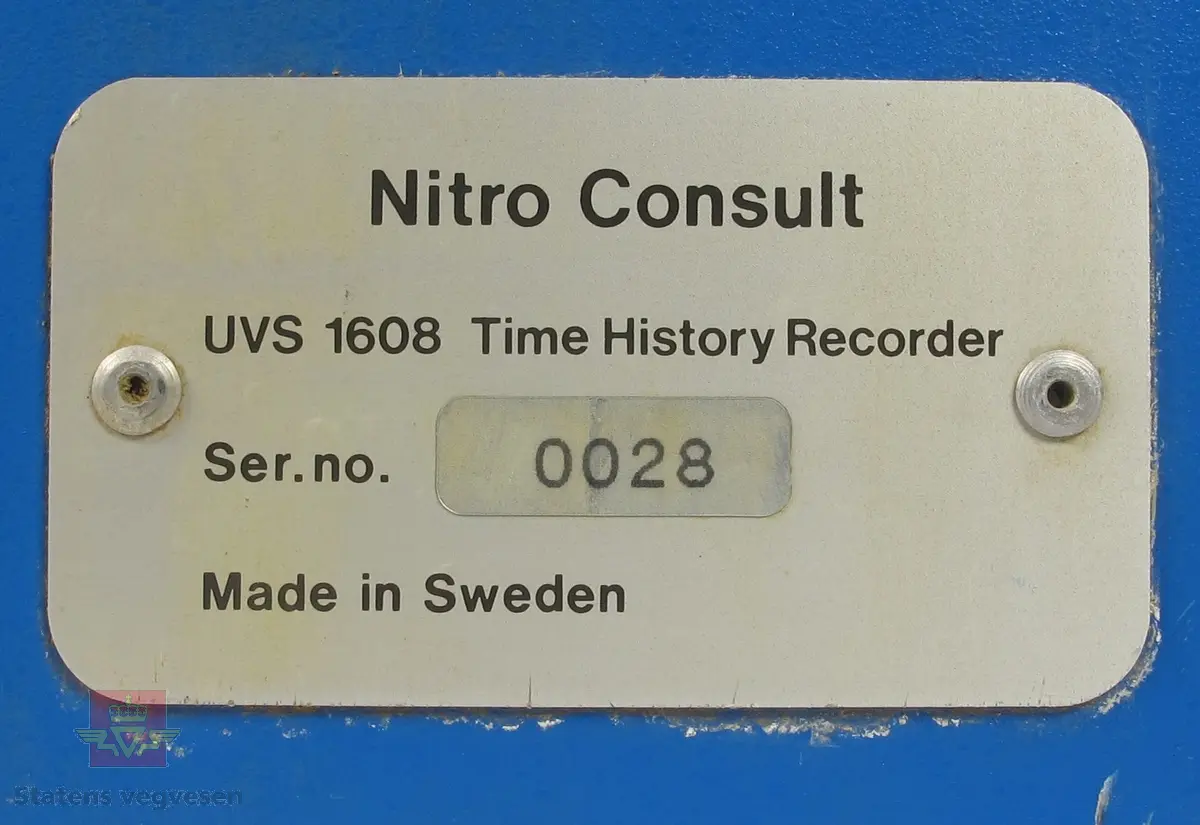Blålakkert vibrasjonsmåler hovedsakelig i metall, med bærehåndtak. Har avtagbart lokk med to hemper for festing. Lokket har klistremerke med påskriften DYNO Dyno Consult AS. På siden av vibrasjonsmåleren er det en skiltplate som har innskriften Nitro Consult UVS 1608 Time History Recorder Ser. no. 0028 Made in Sweden. Betjeningspanelet på vibrasjonsmåleren består av knapper, vindu for avlesning og papirskriver for utskrift. Klistremerke med påskriften DYNO Dyno Consult AS Vækerøvn. 8, Postboks 266 Skøyen, 0212 Oslo 2 Telefon: (02) 73 01 50 Telefax: (02) 73 01 50. Øverst på vibrasjonsmåleren er det flere tilkoblingsmuligheter for kabler.