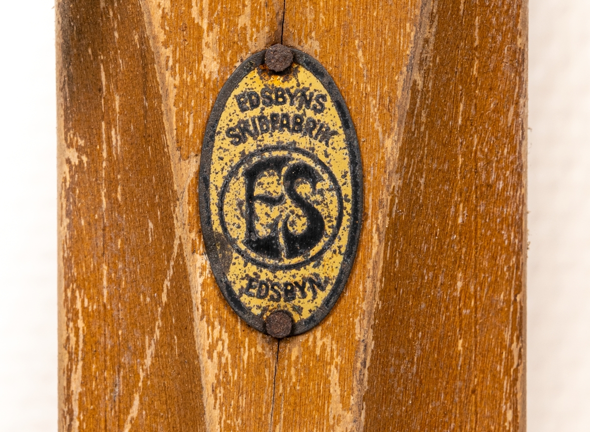 Ett par träskidor med bindningar i metall (rostiga). Märke påklistat med "Edsbyns Skidfabrik".