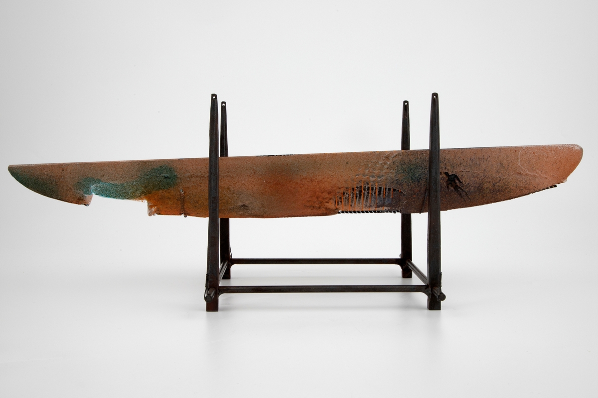 Båtformet skulptur i klart glass, utført ved hjelp av sandstøping. Skulpturens grunnform alluderer til et vikingeskip. De rustrøde sidene har en rustikk overflate, hvor turkisfargede partier tidvis kommer til syne. Inne skulpturen er det innkapslede glass- og metallobjekter, hvis utforming minner om fosiler samt vikingesymboler. Skulpturen bæres av et smijernstativ med fire vertikale pilarer.