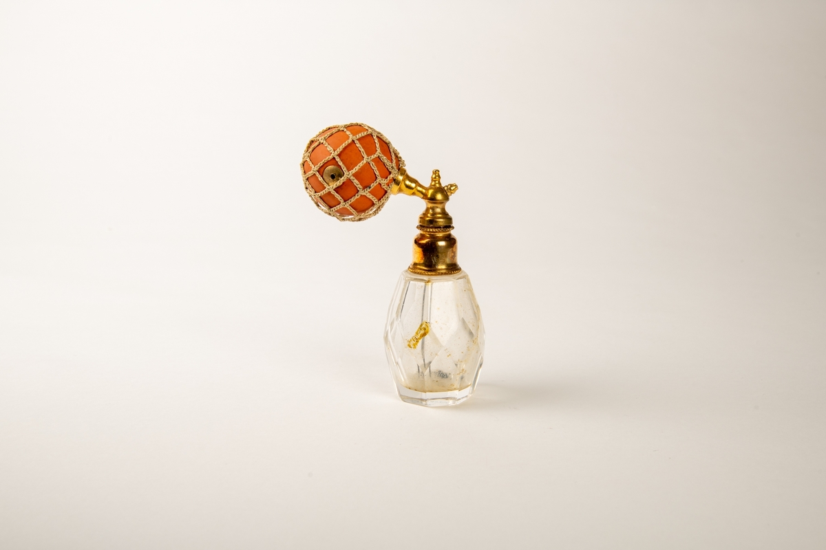 Flakonger i fasettslepet krystall med forgylte topper. Rød gummiballong i grønt trådnett.  Ligger i en såpeeske. Høyde på flakongene: 12 og 10 cm.