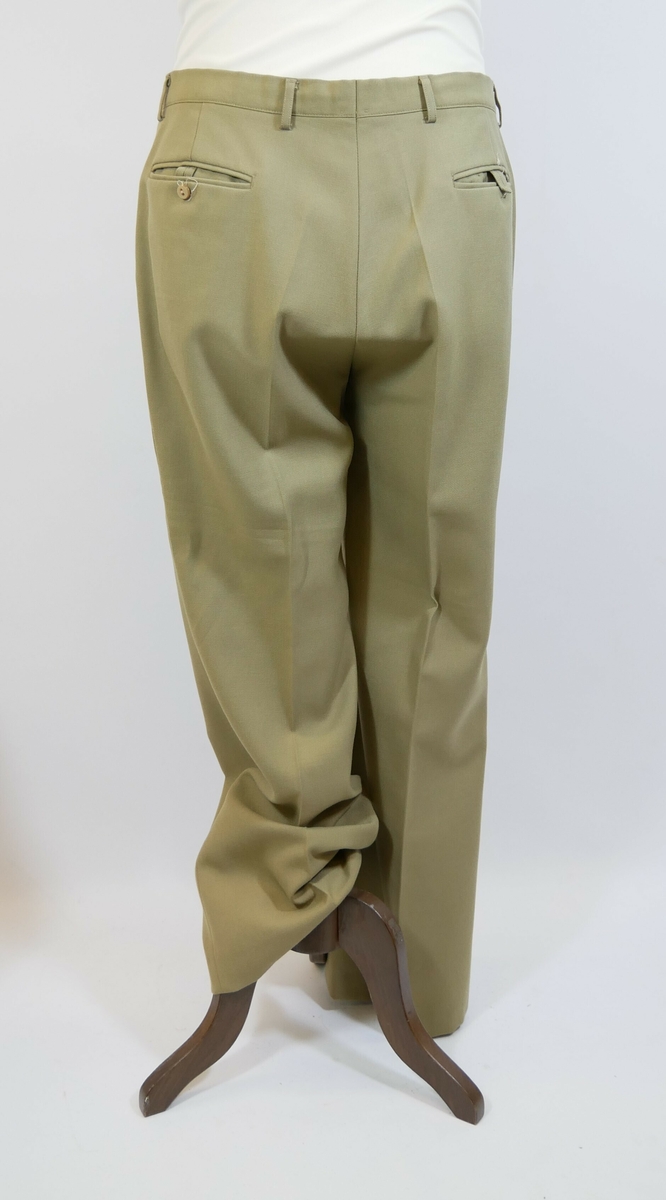 Brun bukse med press. Buksesmekk med glidelås og to metallhekter øverst. To lommer foran og to baklommer. 

Påskrift lapp inne i buksa: 
STYLES BY // KLØVER // 5000 BERGEN
