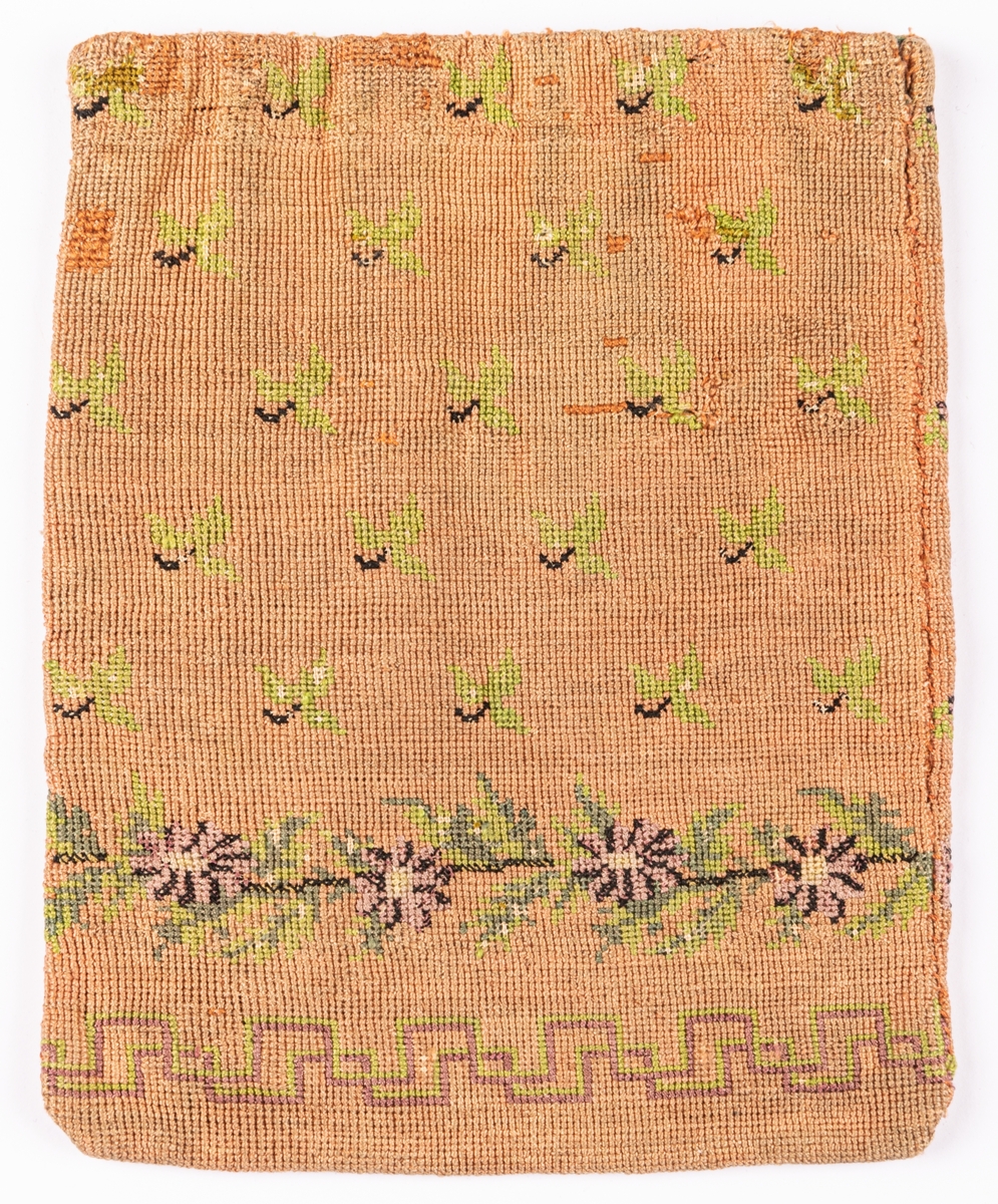 Väska, korsstygnsbroderi i gammalrosa, små blommor och blad strödda, nedtill en ranka i grönt och lila: blommor och blad, nederst en á la greque i grönt och lilka, grönt foder.