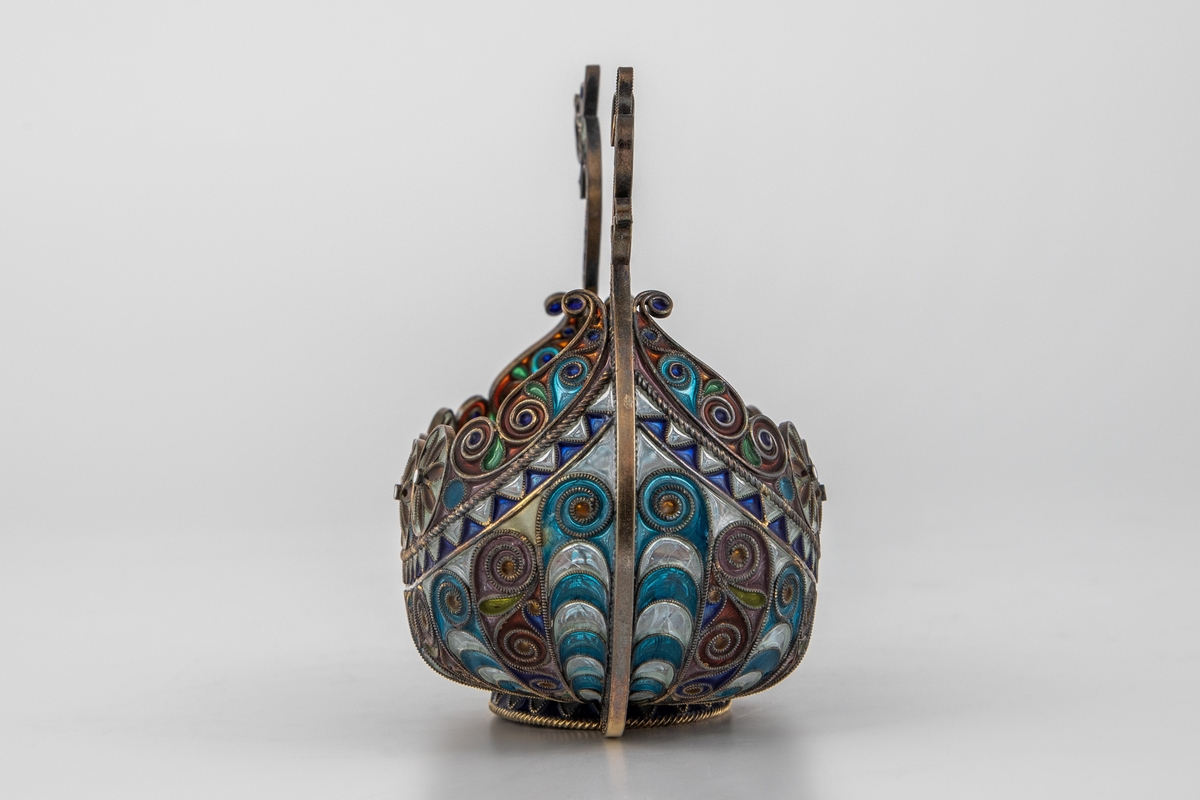 Pyntegjenstand, utformet som et vikingskip, i sølvfiligran og vindusemalje. Oval formet "kjøl" i sølv. Resten av båten er bygget opp av et intrikat filigransarbeid, hvor mellomrommene er fylt med transparent vindusemalje i ulike farger. Filigranstrådene danner rosettformede skjold langs skipets relling, samt voluttornmaenter og s-former på korpus. Forstevnen er utformet som et gapende dragehode, mens akterstaven har avsluttes med blomsterornamenter.