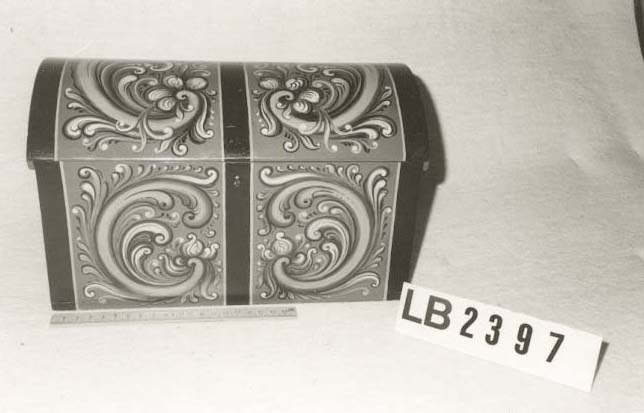 Rosemåla. lita kiste i klare fargar. Tydlege C-krullar både på loket og framme, desse er ramma inn med svarte, måla band.Raud botnfarge. Einsfarga sider og bakside. Umåla under botn. På Baksida er det måla DALEN.  Inni har kista eit lite rom på den eine sida. Grønmåla inni. Kuva lok. Lås med nøkkel.