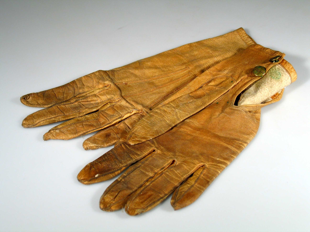 Håndlov og håndbak er skåret i ett. Søm i siden, tre innfellinger mellom fingrene, hver med søm i bukten. Tommel med innfelling for hver bevegelighet. 8,5 cm splitt mot underside av håndledd. To skonnerte knapphull og to knapper. Tre doble stikninger i vifteform på håndbaken.