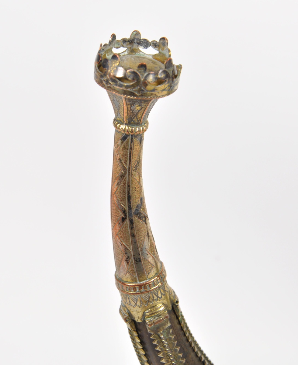 Drikkehorn med metallbeslag rundt kanten, to ringer rundt hornet, et beslag på spissen og smale langsgående beslag. Den største ringen har fester for støttebein. De nåværende beina er ikke de opprinnelige. Beslagene er av forgylt bronse. Krone i spissen. Graverte beslag med geometriske border.