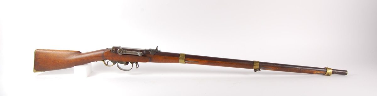 Militært kammerladningsgevær M 1849/55. Rund riflet pipe med militær norsk kammerladningsmekanisme. Kammeret er hengslet i bakkant med hevarm på høyre side. Underliggende hane ( Perkusjonslås ).
Messing bånd, underbeslag, frontsikte og kolbekappe.
(Fint eksemplar)