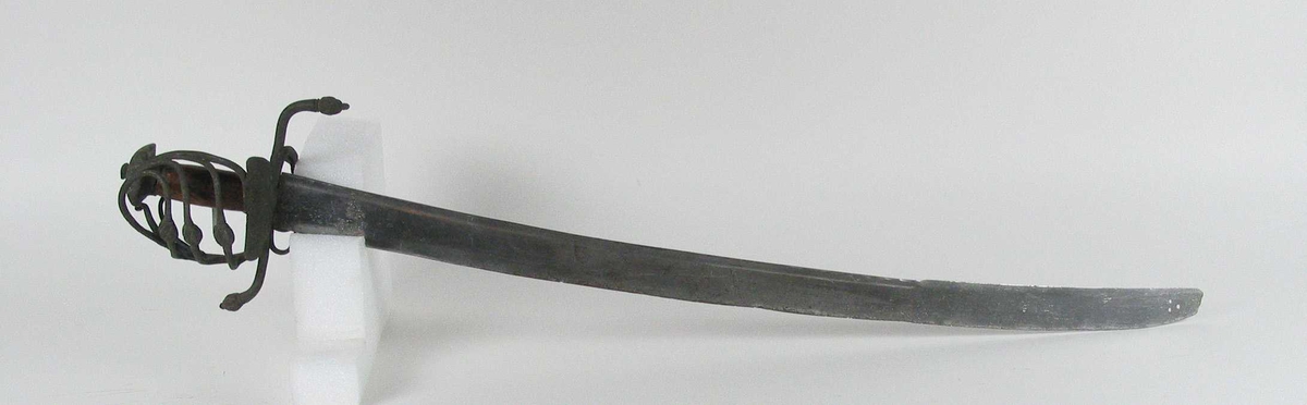 Pyramideformet knapp med kryssfilt dekor og asymmetrisk feste med 3 sidebøyler med fortykninger på midten på utsiden og en på innsiden. Nyreformet parerplate på utsiden og klingebrekker og tommelbøyle på innsiden. S-formede, runde parérstenger med fortykning med filt dekor og dråpeformet avslutning.
Tregrep. Enegget krum, kileformet klinge med en ryggstillt blodrand. Ryggslipt mot spissen. Spiss brukket. Tre hull på spiss. Ett smedstempel.

