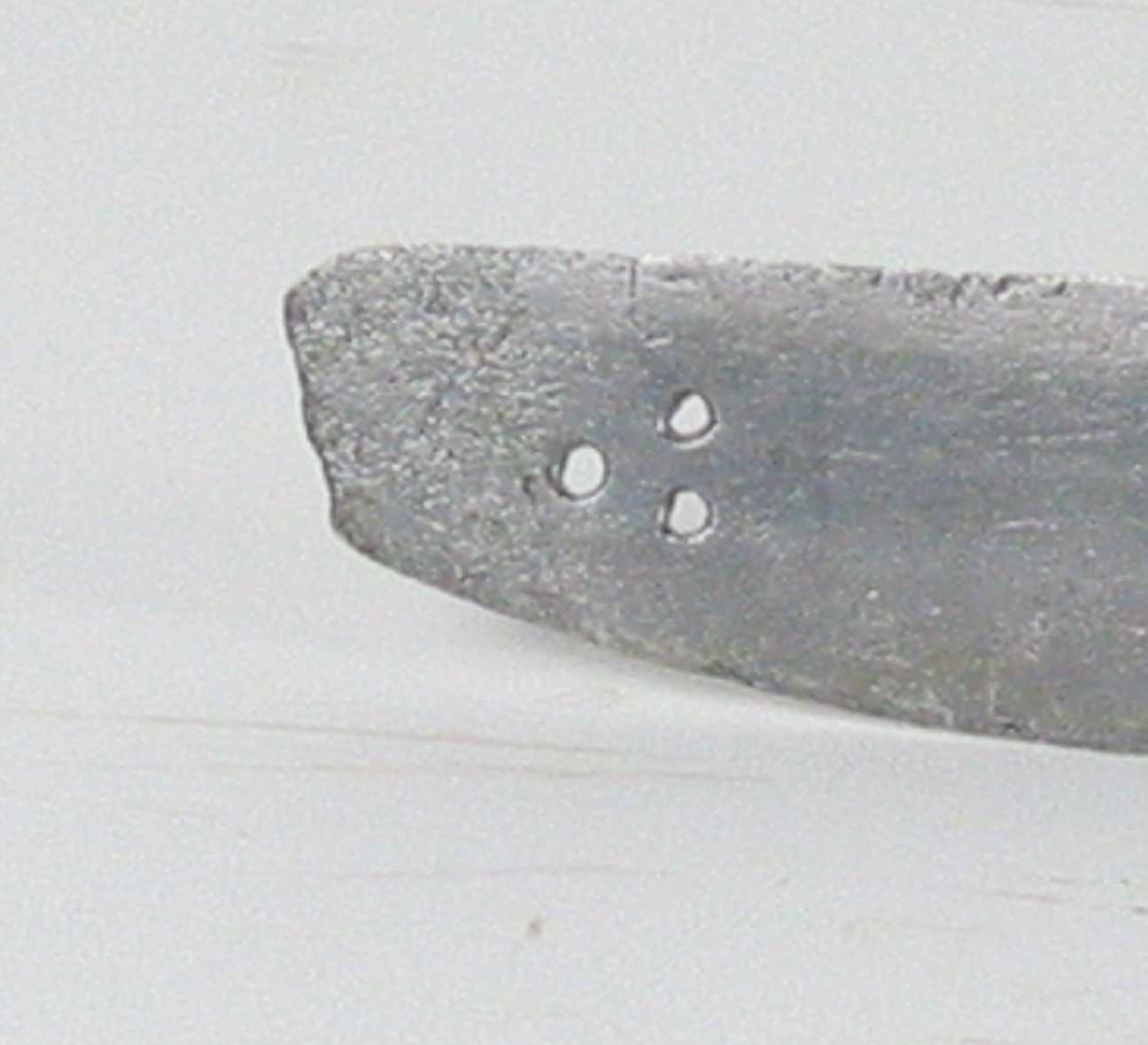 Pyramideformet knapp med kryssfilt dekor og asymmetrisk feste med 3 sidebøyler med fortykninger på midten på utsiden og en på innsiden. Nyreformet parerplate på utsiden og klingebrekker og tommelbøyle på innsiden. S-formede, runde parérstenger med fortykning med filt dekor og dråpeformet avslutning.
Tregrep. Enegget krum, kileformet klinge med en ryggstillt blodrand. Ryggslipt mot spissen. Spiss brukket. Tre hull på spiss. Ett smedstempel.


