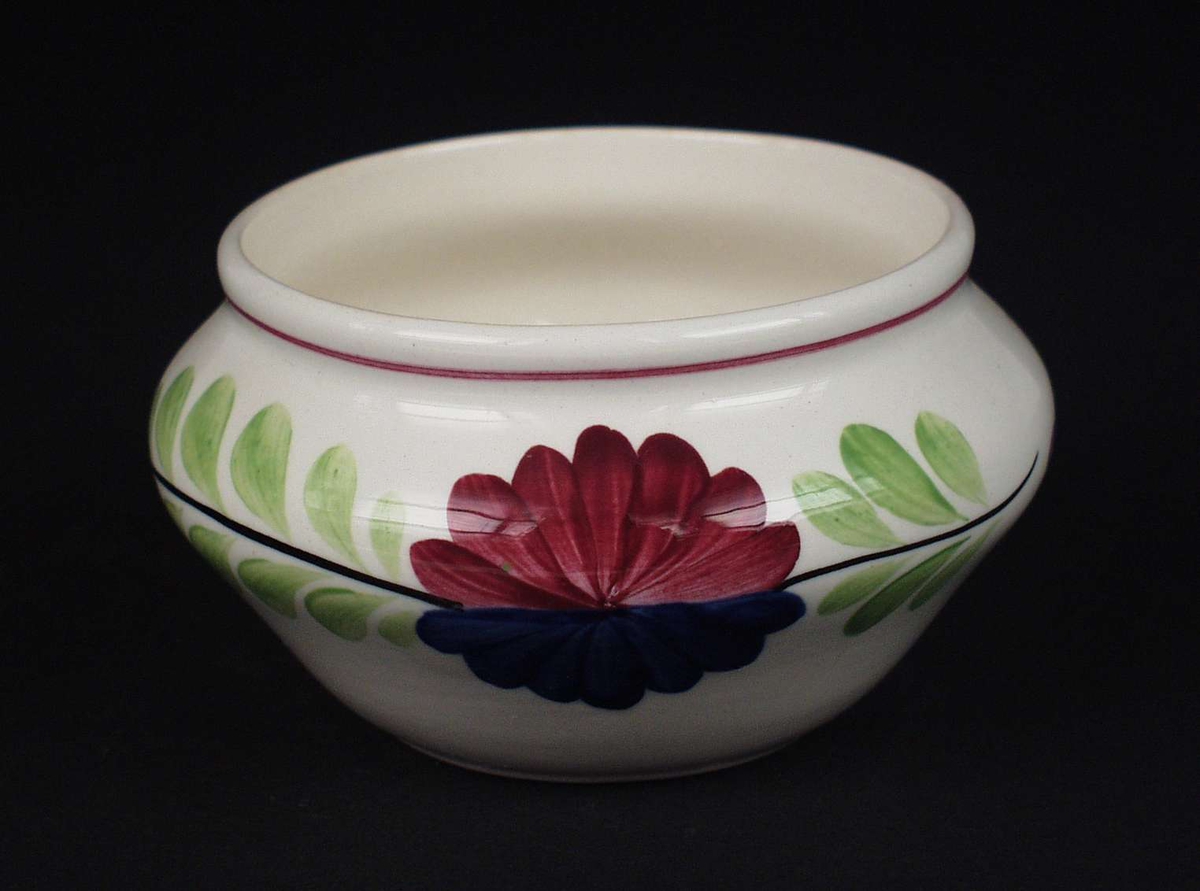 Deler av servise i steintøy og flintgods. Godset er hvitt med malt blomsterdekor. Rød og blå blomst i midten med en ranke av grønne blad.