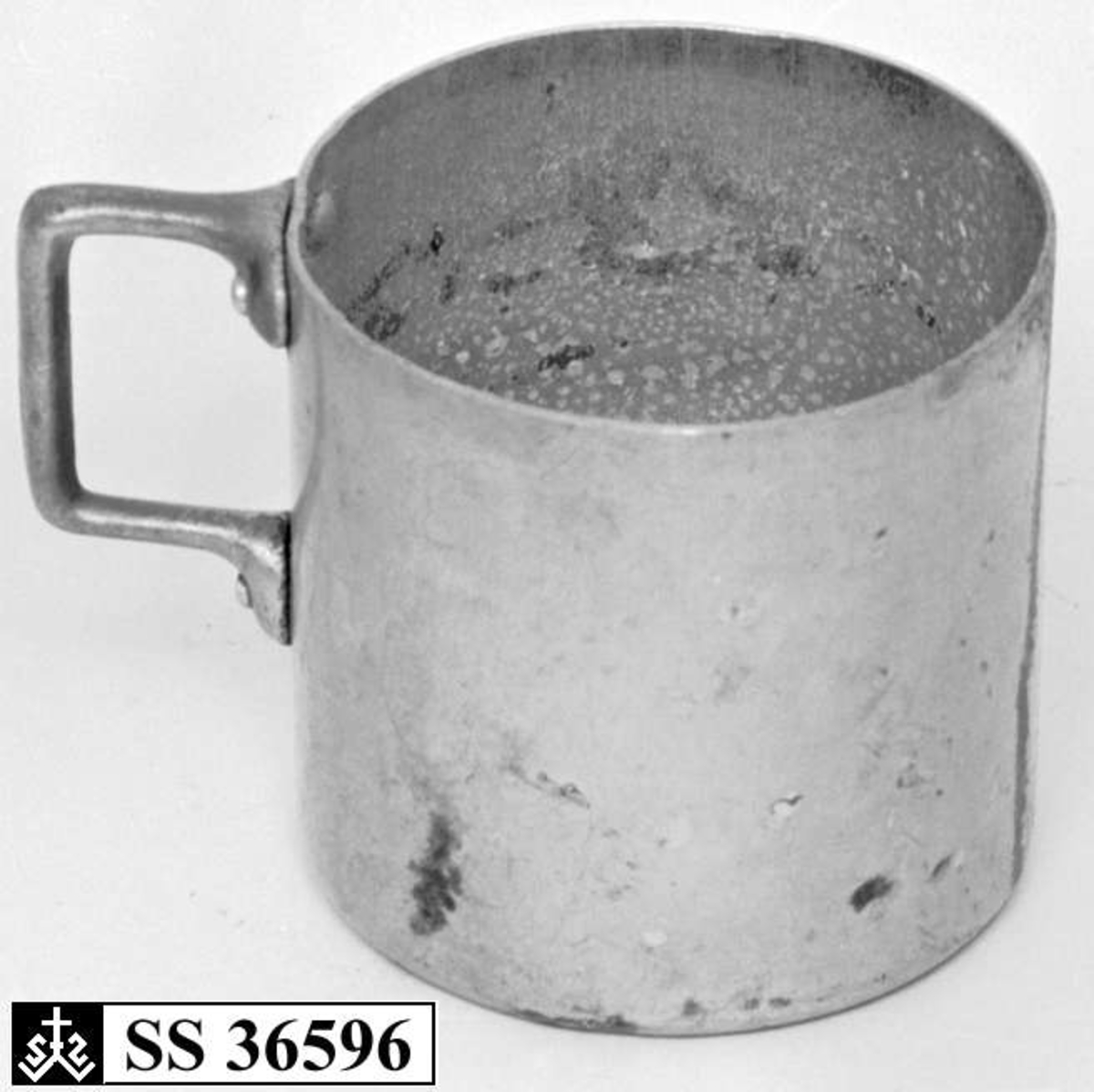 Kopp eller målebeger laget i aluminium. Hanken er naglet fast til koppen.