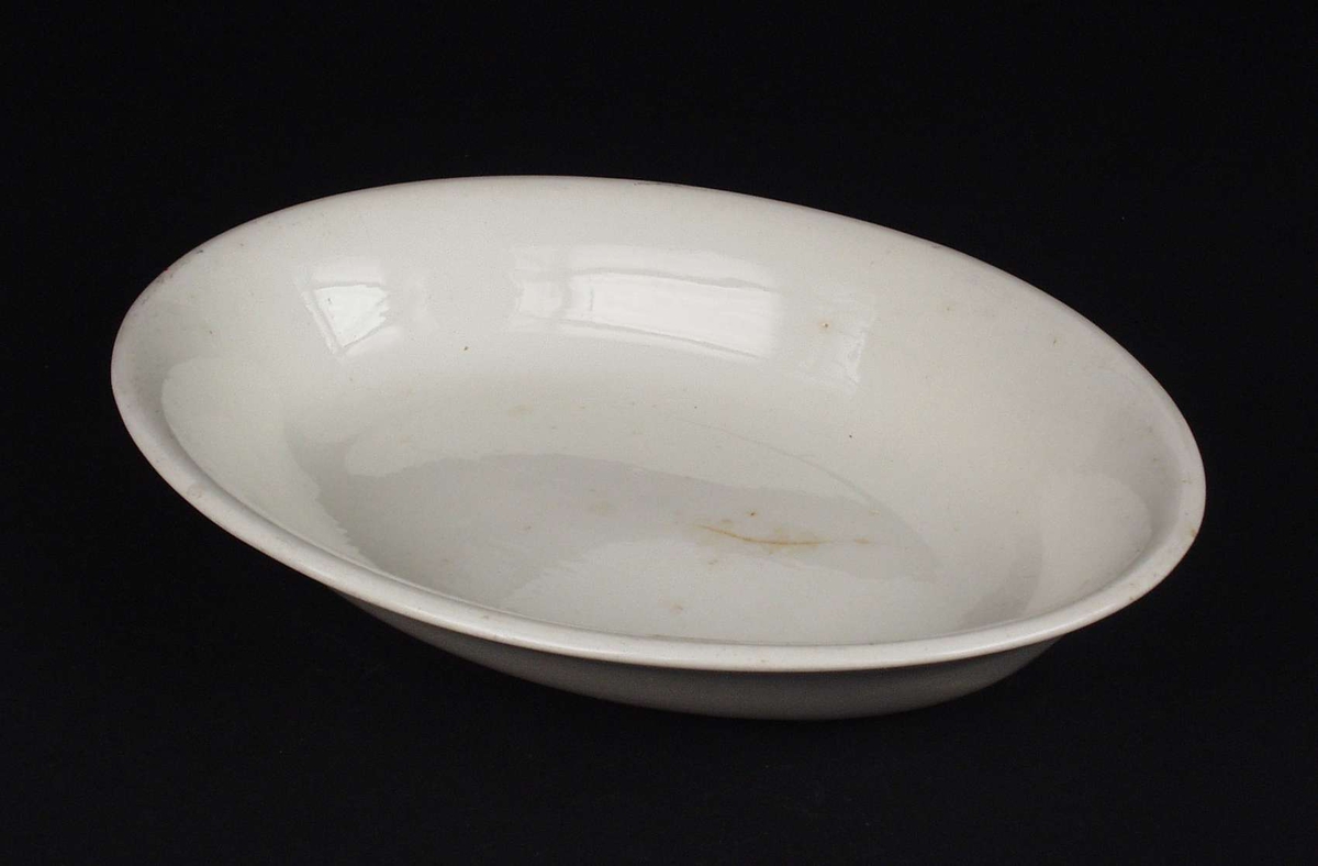 Hvitt ovalt serveringsfat laget i steintøy.