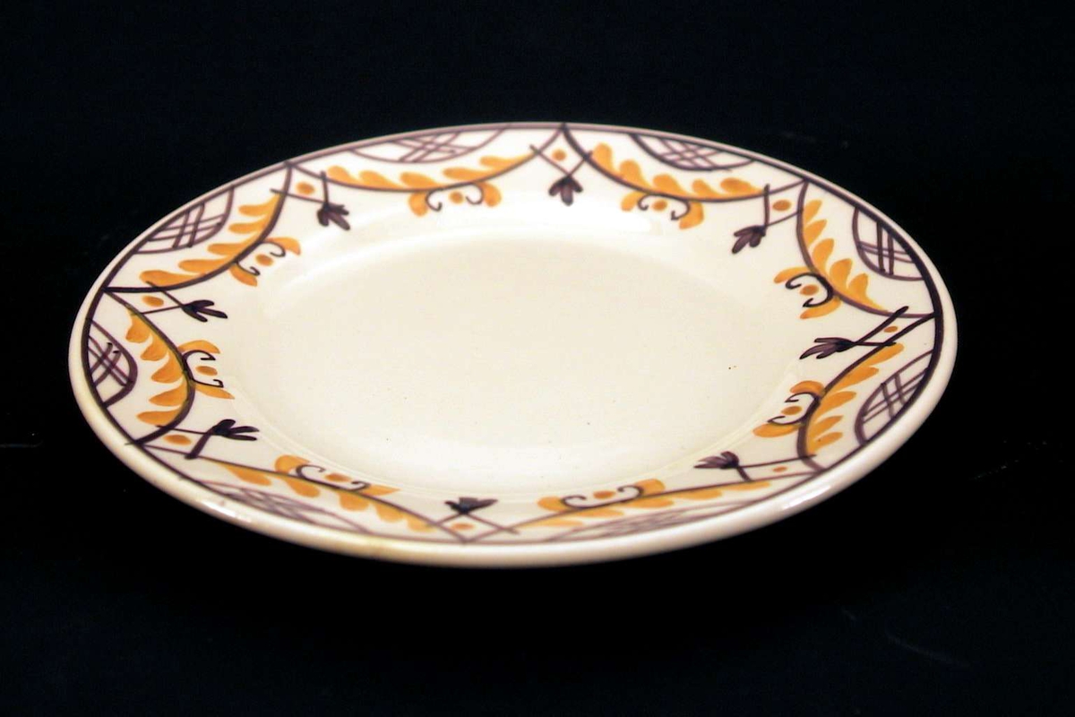 Asjett i lys gul fajanse med håndmalt dekor i lilla og oker. 