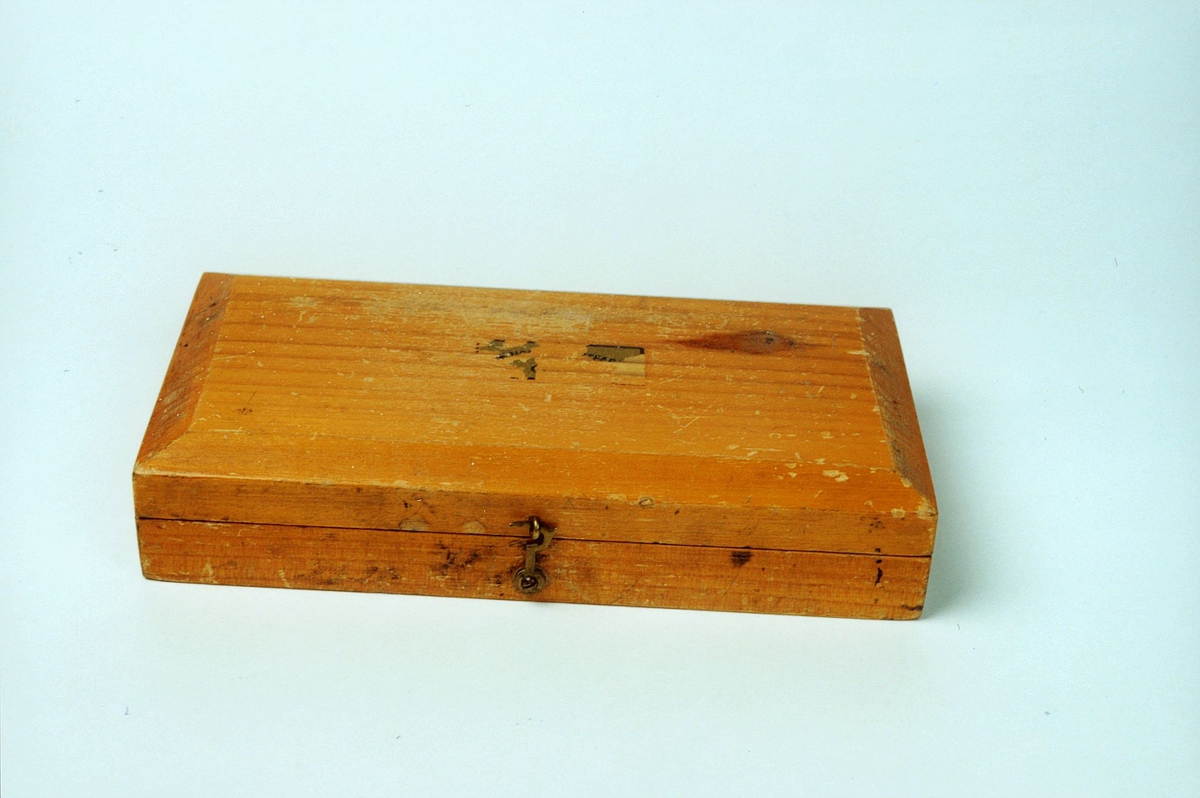 Loddkasse av tre  og inneholder 8 lodder i messing på 500, 250, 125, 100, 40, 2x20 og 2 g. 2x10, 5, 2 og 1 g mangler.