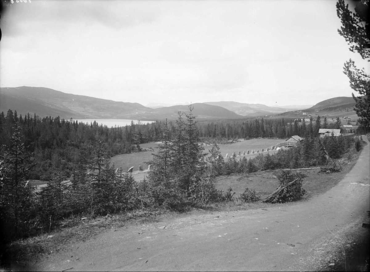 Rogne og Voldbo (Volbu) set fra Rogne kirke.  Valdres  27.06.1907, veier, bygninger, skog, fjell, sjø.