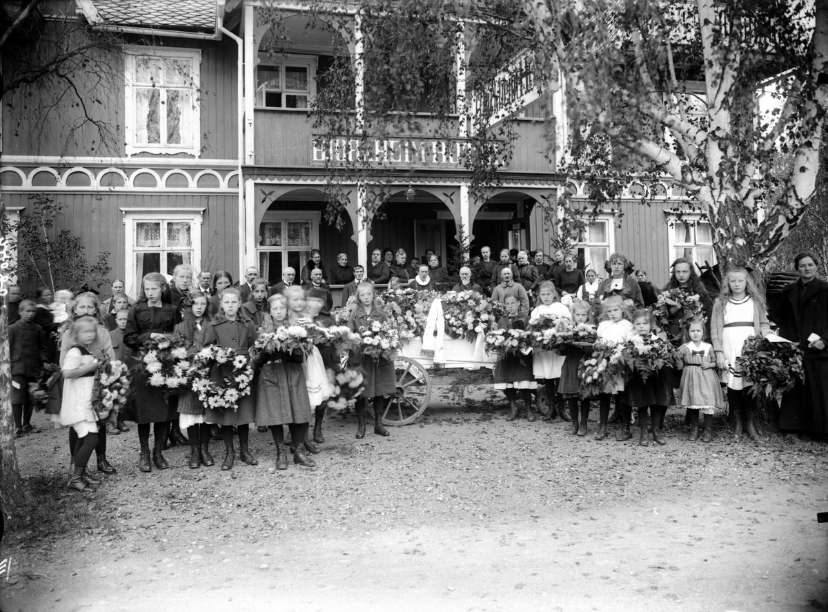 Kort:  Sel (Otta). Begravelse, begravelsesfølge, pyntet båre, kranser, (Bjørkheim hotel i bakgrunnen)